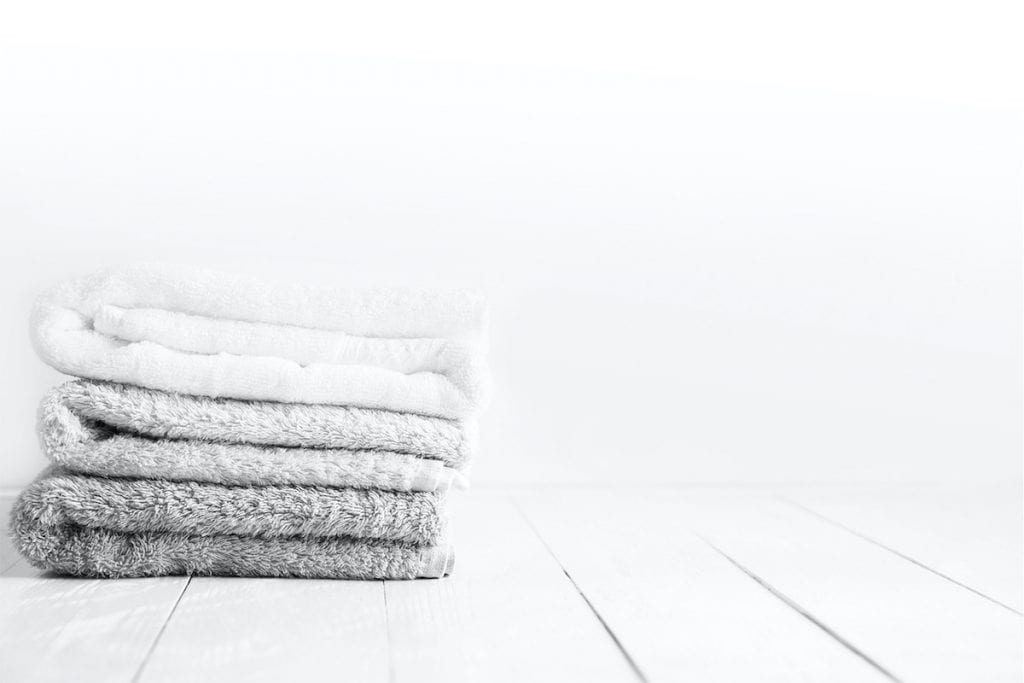 Stack of clean towels on wooden table in bathroom