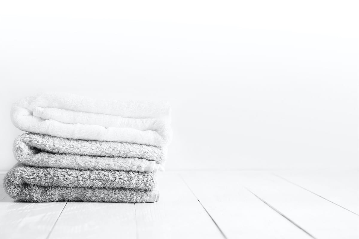 Stack of clean towels on wooden table in bathroom