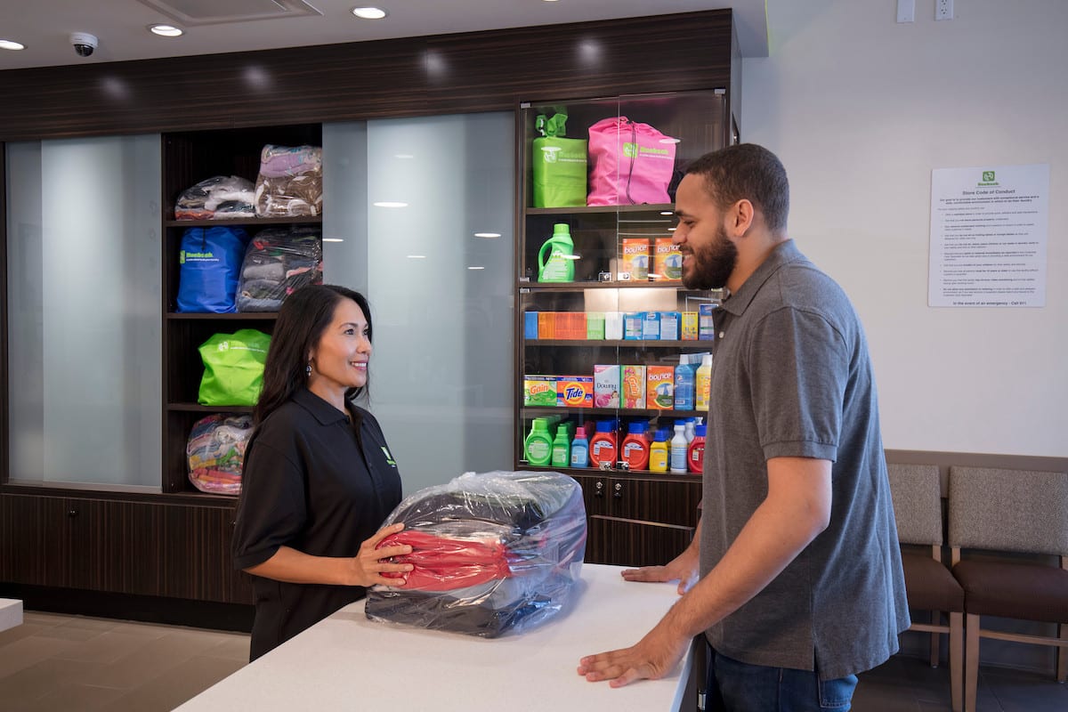 man collecting laundry from worker at laundromat