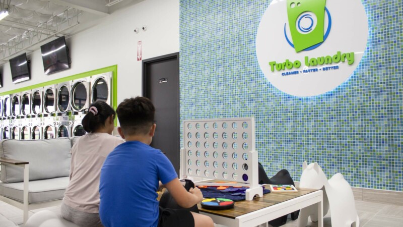 Entrepreneurs two kids playing Connect 4 at the laundromat