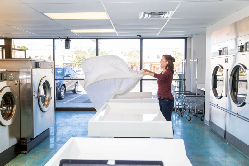 woman folding sheet at laundromat