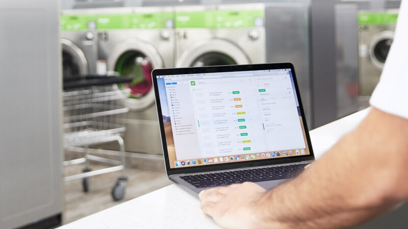 employee standing at laptop inside laundromat looking at insights