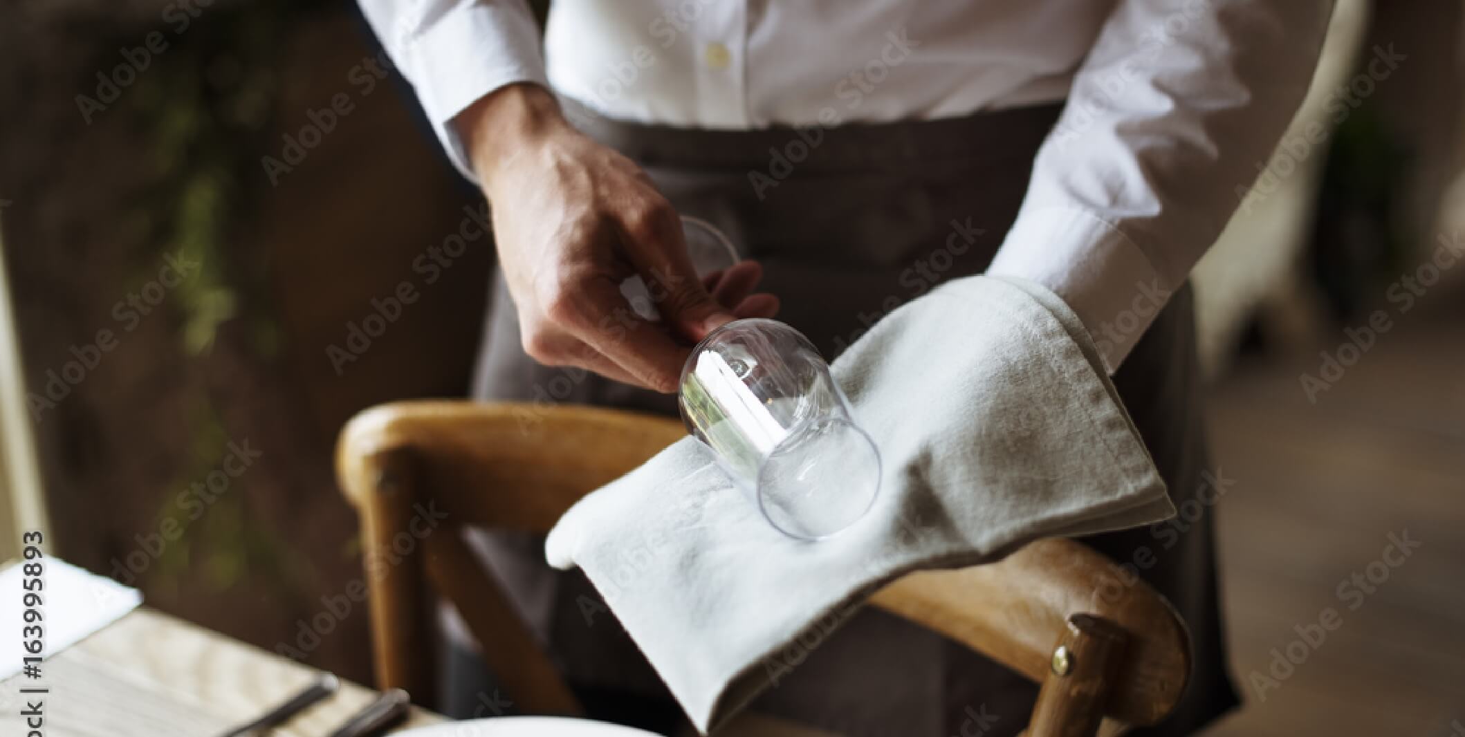 server holding wine glass and linen napkin
