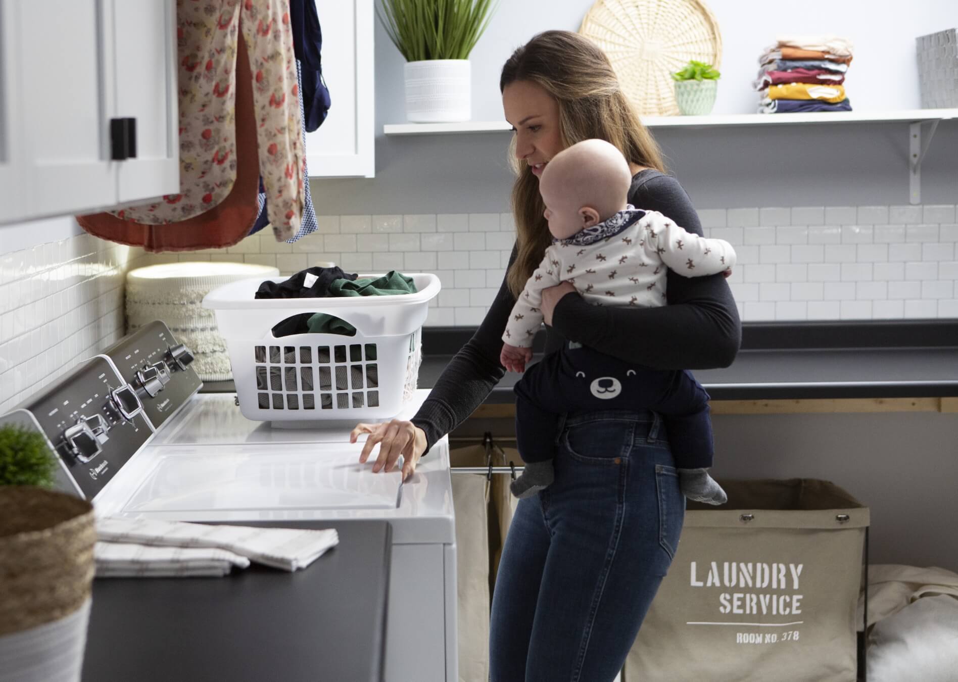 mother holding baby and doing laundry