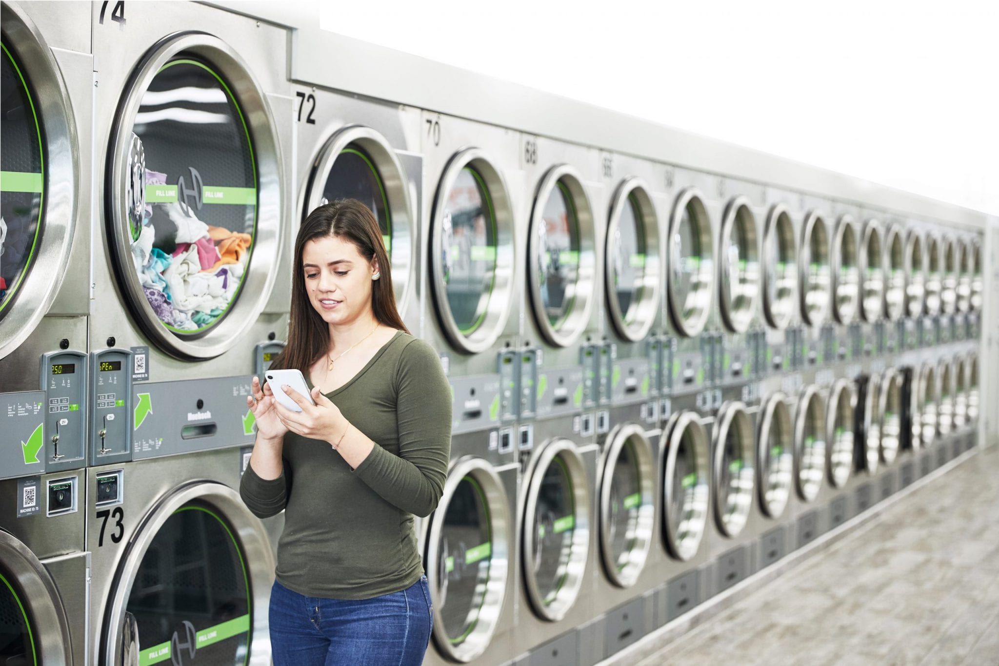 woman smiling at her phone at a Huebsch laundromat