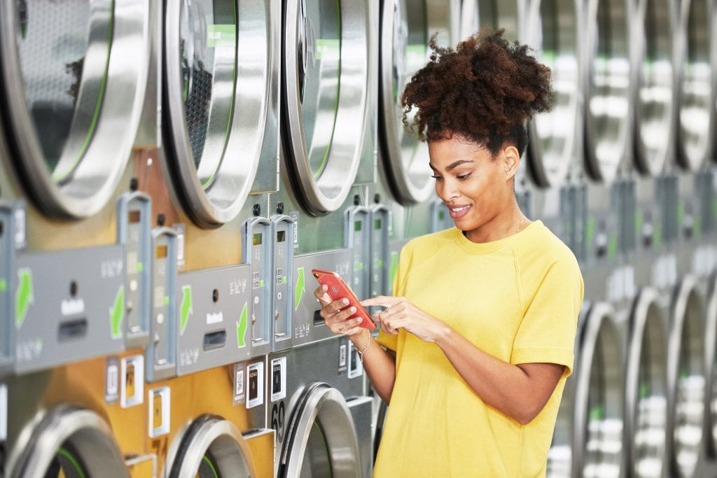 woman smiling at her phone at a laundromat