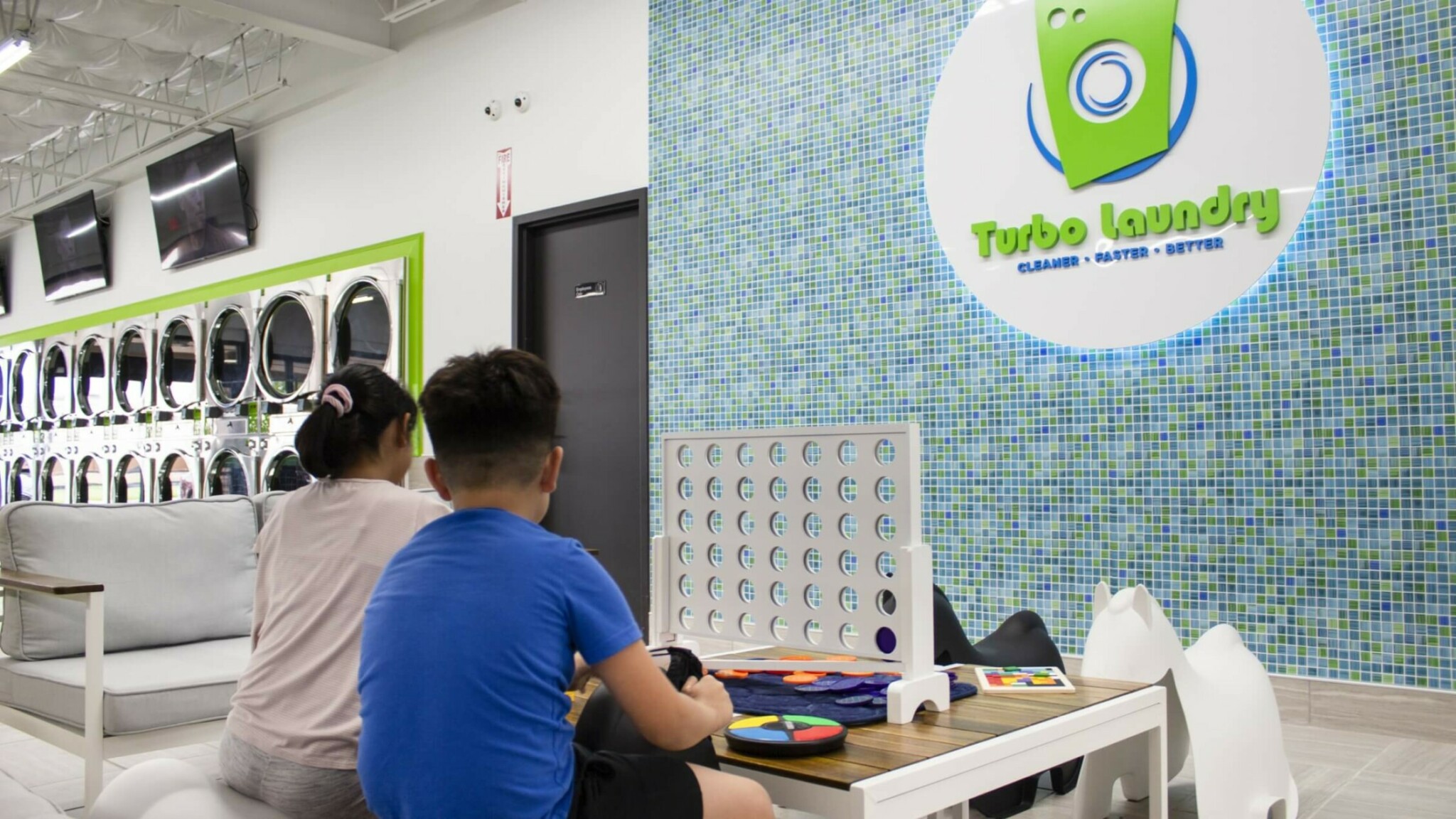 two kids playing Connect 4 at the laundromat